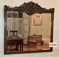 Full front view of rectangular oak mirror showing carved top and side aprons and reflective surface.