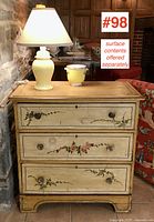 Front view of three-drawer pine chest showing hand-painted floral design and surface contents