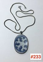 Full view of the sterling silver mounted pottery shard pendant with attached silver chain arranged flat.