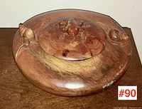 Top view of the wooden circular box showing carved frog on lid and one snail on side rim.