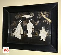 Framed artwork of three Chinese carved figures in relief with dark background and decorative trees and foliage.