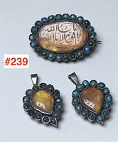 Front view of oval brooch with engraved amber and turquoise border, accompanied by two teardrop pendants