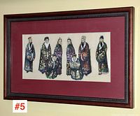 Full view of framed print showing eight figures in colorful traditional robes against a red mat in a carved wood frame