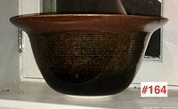 Side view of the large studio pottery bowl showing dark glossy glaze and broad flared rim.