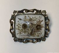Front view of rectangular brooch showing full pressed flower arrangement under glass