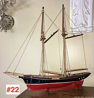 Side profile showing the ship's hull painted red and blue with rigging attached to two masts