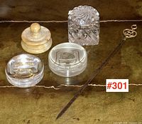 Collection of three glass paperweights with animal motifs, carved ivory/bone round item, glass inkwell, and long metal letter opener placed on a leather surface.