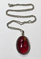 Full view of necklace showing oval red glass pendant and twisted rope chain with lobster clasp