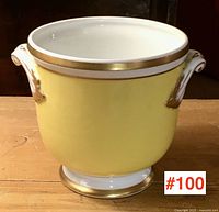 Front view of yellow porcelain cache-pot showing gold rim and base with white handles accented with gold.