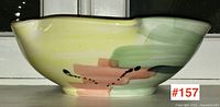 Side view of pottery bowl showing yellow, pink, and black dotted abstract design with pouring spout