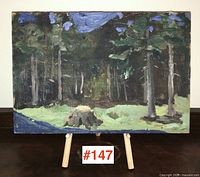 Front view of the small painting on board showing the forest landscape with trees and stump, placed on an easel with lot number.