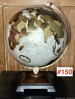 Full view of the vintage globe showing the continents and its mounted wooden and metal base.