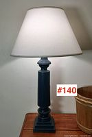 Full view of the vintage wooden table lamp with white fabric shade on wooden surface.