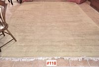 Full view of cream wool rug laid flat on tiled floor showing overall size and condition.