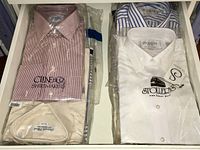 Top view of plastic-wrapped dress shirts in drawer, showing multiple packaged shirts.