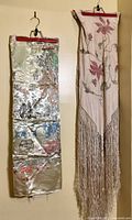 Photo showing both silk tablecloths hanging side by side on hangers against a wall, highlighting the different colors, designs, and finishes.