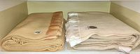 Two folded wool blankets side by side on shelf