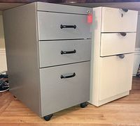Two office filing cabinets under desk, one gray and one white with drawers and locks