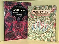 Two hardcover books standing side by side against a wall, titles visible.