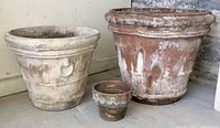 Set of three terra cotta pots showing two large and one small pot