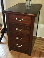 Front angle view showing four drawers with metal handles and wood grain visible on drawer fronts and top surface.