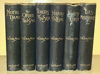 Six hardcover Victor Hugo books with black spines and gold text, titles: Notre Dame, By Order of the King, Toilers of the Sea, History of a Crime, Ninety-Three, Les Miserables.