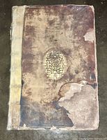Front cover showing full leather boards with vellum spine and areas of leather loss