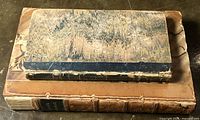 Two antiquarian books stacked, showing condition and cover details.