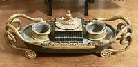 Front view of the bronze inkstand showing serpentine handles, twin inkwells, central lidded reservoir