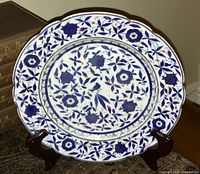 Front view of the antique porcelain plate on a wooden stand, showing overall design and condition.
