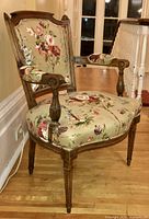 Side three-quarter view of the carved wood frame and upholstered seat backs