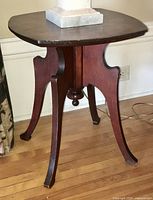 Front angle view of antique wooden side table showing curved legs and top surface.