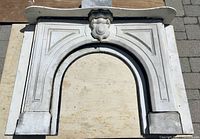 Full front view of the slate fireplace surround laid flat on wooden boards showing overall arch shape and shelf.