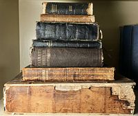 Stack of seven antique Bibles showing varied bindings and heavy wear, edges and spines damaged