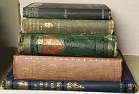 Stack of six assorted antique books showing varying colors and spine conditions
