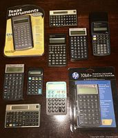 Nine assorted vintage pocket calculators arranged on a surface, some loose, some in packaging.