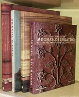 Four vintage art books stacked; the foremost book is 'The Majesty of Mughal Decoration' with a floral embossed stone relief cover image.