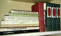 Shelf view of assorted vintage banking and financial books including histories of major Canadian banks and government financial reports.