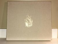 Beige cloth slipcase with gilt embossed sailing ship image on the front.
