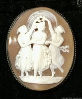 Full front view of the oval cameo brooch depicting three classical women, showing overall design and condition.