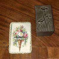 Cast iron trinket box placed on wooden surface next to a floral lace-edged card