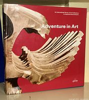 Front cover of the 'Adventure in Art' hardcover book showing a winged sculpture image on a red background.