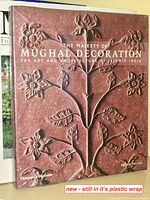 Front cover of 'The Majesty of Mughal Decoration' art book showing embossed floral design and title.