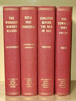 Full set of four red cloth-bound hardcover books on a shelf showing spines