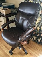 Angled front view showing padded seat, backrest, armrests and caster base