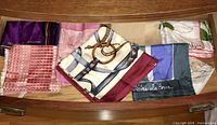 Drawer view showing six folded ladies silk scarves of various colors and patterns.