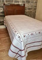 Full view of single size bed with pine headboard, metal frame and quilted cover