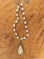 Full view of necklace laid flat on wooden surface showing chain, cabochons, and teardrop pendant