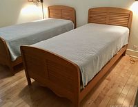 Two twin bed frames and mattresses side by side on wood floor