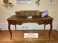 Front view of desk with leather inlay top and curved legs
